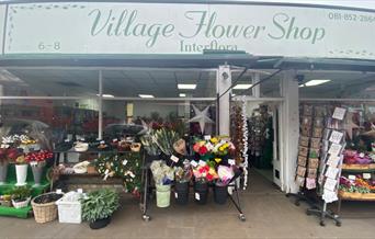 Outside Village Flower Shop in Blackheath. Showing a Green and White Themed Shop with Multiple Rows  of Stunning Flowers.