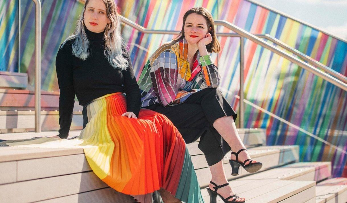 Artist Liz West and Designer Kitty Joseph adorned in her bright colour signature collection in front of the art installation on The Tide.