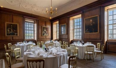 White banqueting rounds on wooden floor and pictured walls at the Admiral's House, Old Royal Naval College