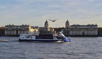 City Cruises boat on river Thames with Old Royal Naval College in the background