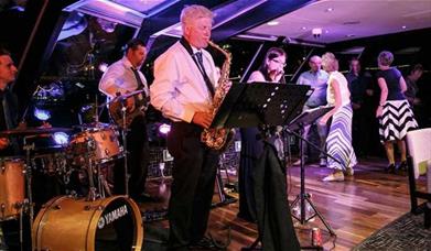 Jazz Band performance taking place onboard City Cruises Jazz Dinner Cruise with guest dancing on the dance floor.