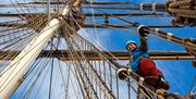 Woman climbs the the rigging at the Cutty Sark Rig Climb