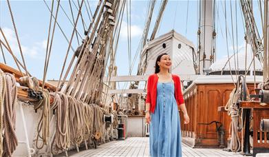 A lady stands on the upper deck of Cutty Sark in Greenwich, London.