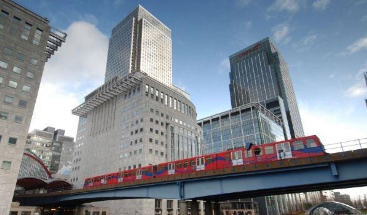 Docklands Light Railway train moves along a bridge among the skyscrapers of Canary Wharf.