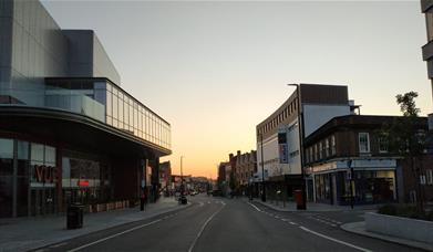 Eltham High Street on a lovely sunset evening, showing a long road filled with shops, entertainment and more.