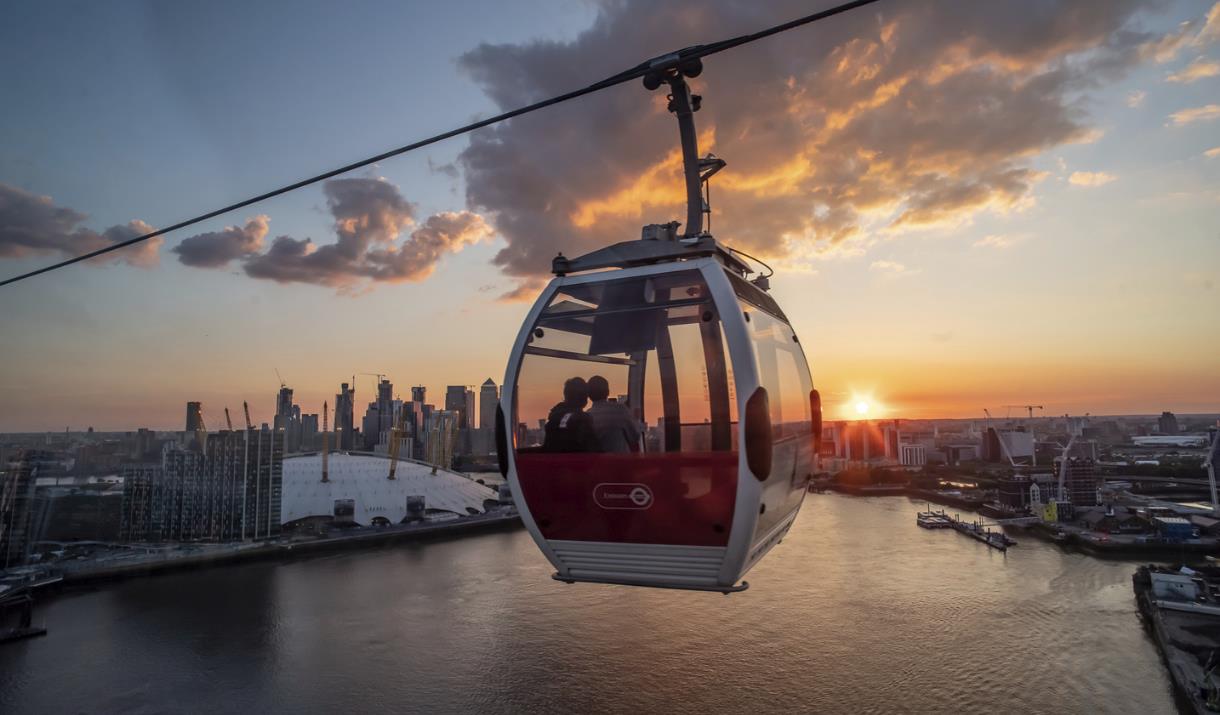 The Emirates Air Line flies over the river Thames from Greenwich Peninsula to Royal Docks at sunset.