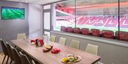 Inside one of Charlton Athletics Executive Boxes, showing a room with a dining table and chairs, a tv with the live game, access to your own outdoor s