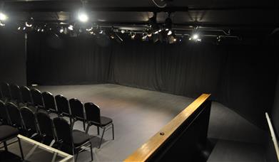 A blacked out studio room with a seating area and performing area.