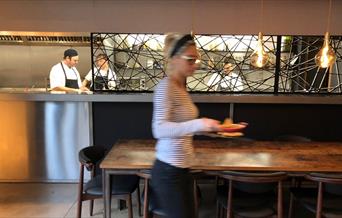 A waitress carries plates of food from the kitchen at The Guildford Arms in Greenwich.