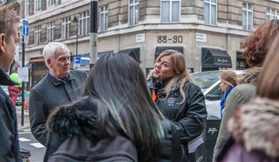 A tour guide gives a tour on a street in London.