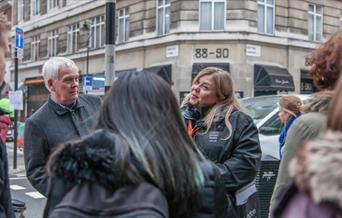 A tour guide gives a tour on a street in London.