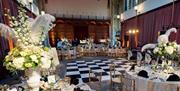 A black and white dancefloor in the middle of white banqueting tables at the Medieval Great Hall, Eltham Palace and Gardens