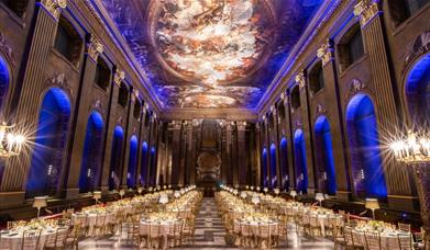 white banqueting round tables setup in the Painted Hall for formal dinner with blue lighting