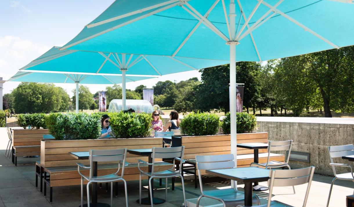 Outside seating at the Parkside Cafe, showing multiple seating areas, benches and the option for big umbrellas.