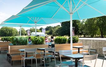 Outside seating at the Parkside Cafe, showing multiple seating areas, benches and the option for big umbrellas.