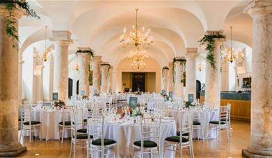 white banqueting round tables and dressed columns for a formal dinner at the Queen Mary Undercroft, Old Royal Naval College