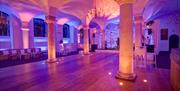 Reception space and columns in purple lighting at the Queen Mary Undercroft, Old Royal Naval College