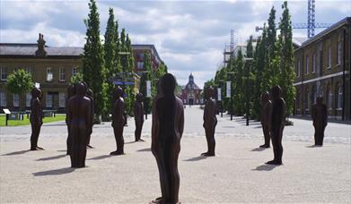A view along Number One Street in Royal Arsenal, Woolwich, featuring the famous "Assembly" statues by Peter Burke.