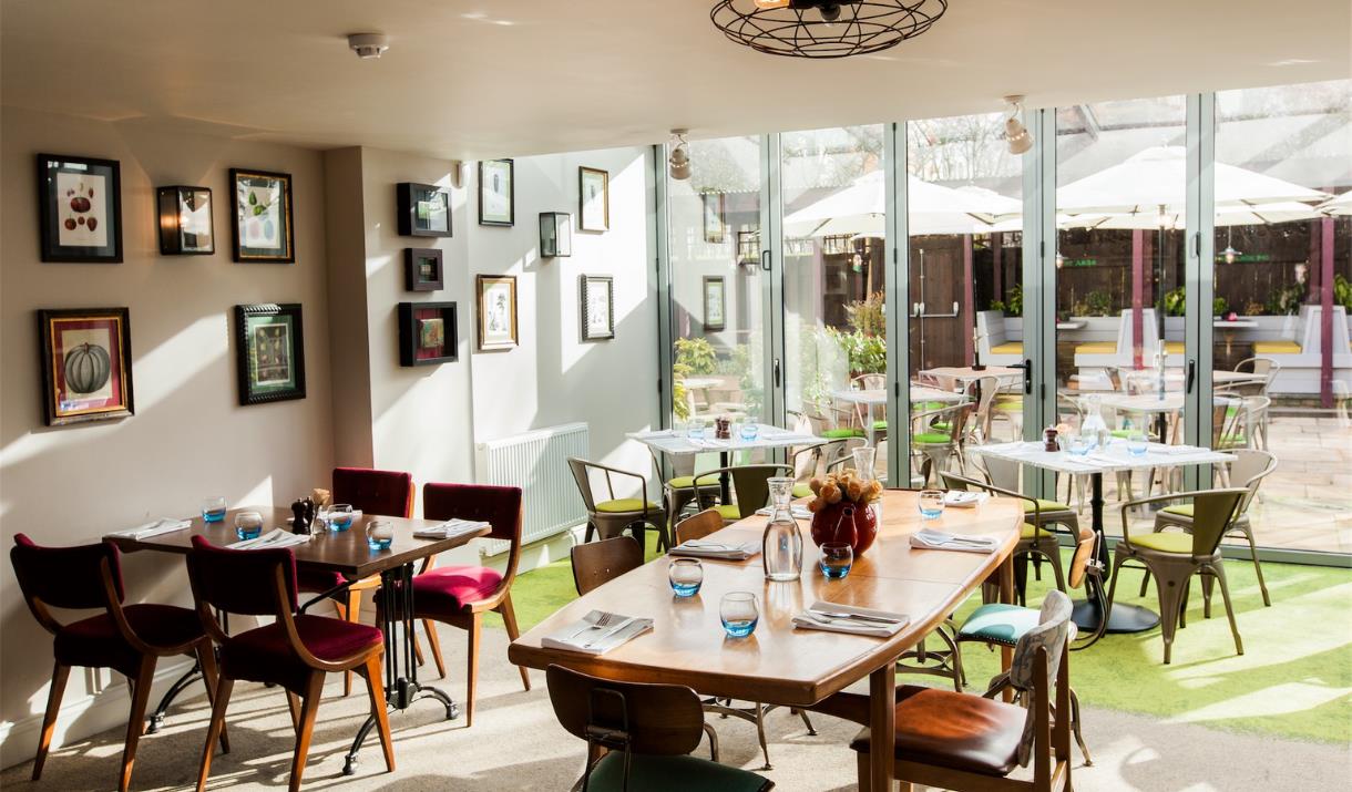 The dining room at The Pilot is bright and airy and overlooks the garden through floor to ceiling glass doors.