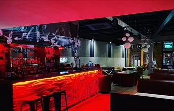 BARCODE restaurant - Left side, the bar is lit with red light and bar stools kept in front. On the right, side and back there are seating booths.