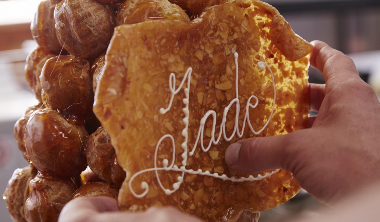 In the image, the Jade Boulangerie pastry chef is adding a display with 'Jade' written to the stack of profiteroles.