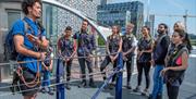 Group of people stood at the start of the climb at Up at The O2 overlooking buildings on Greenwich Peninsula